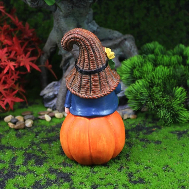 Gnome figurine on a pumpkin with a pointed hat in a garden setting