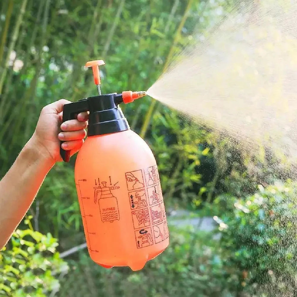 Orange spray bottle being used to water plants with a blurred green background