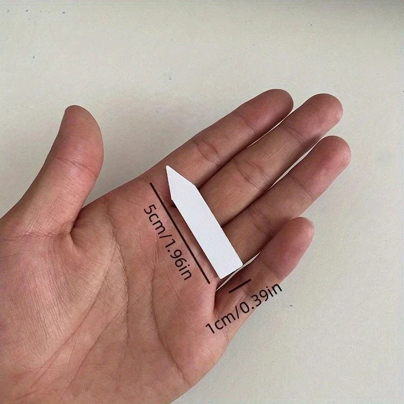 White triangular object held between fingers with measurements indicated
