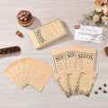 A styled flat-lay of coffee seed packets and a matching envelope on a light wood surface, surrounded by coffee beans, a small wooden box, dried flowers, and a card reading 'BETTER ME'. The packets are kraft paper with black printed text including 'SEEDS' and 'LET LOVE GROW'.